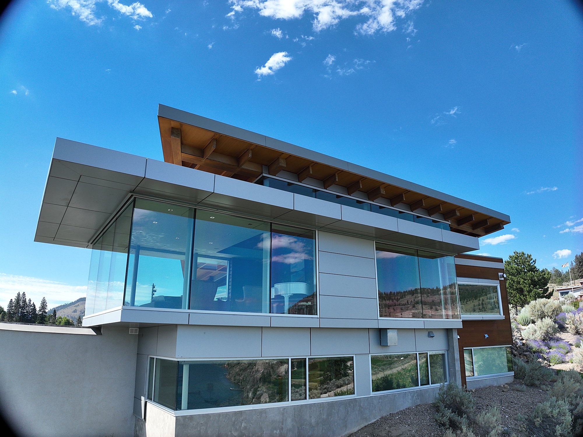 Architectural oblique of a modern glass estate against open sky near Summerland, BC, framed as the property's strongest angle.