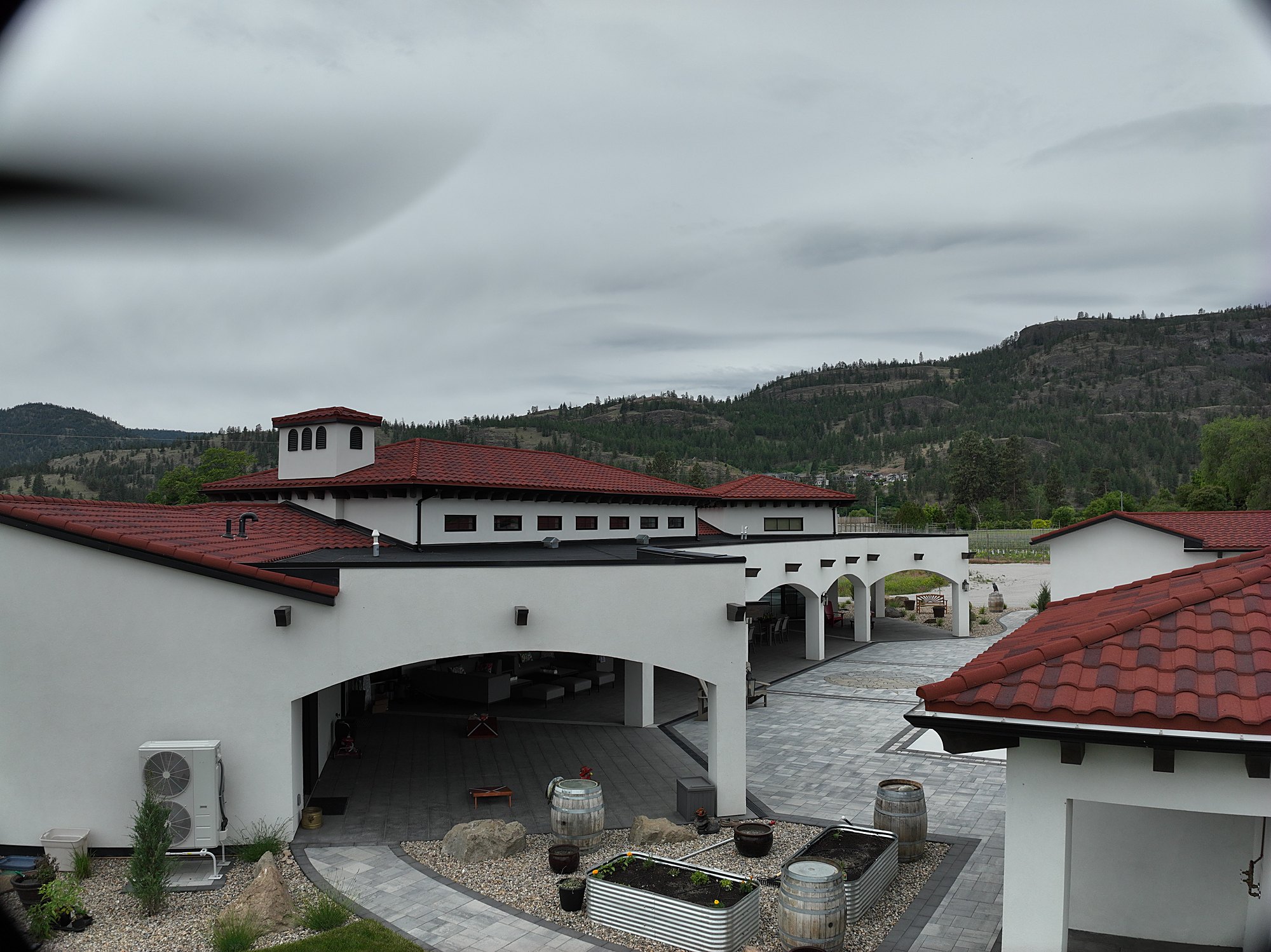 Grand red-roof estate with its full grounds and the hills behind, shot from the air, the kind of high-value Kelowna address that sells on presentation.