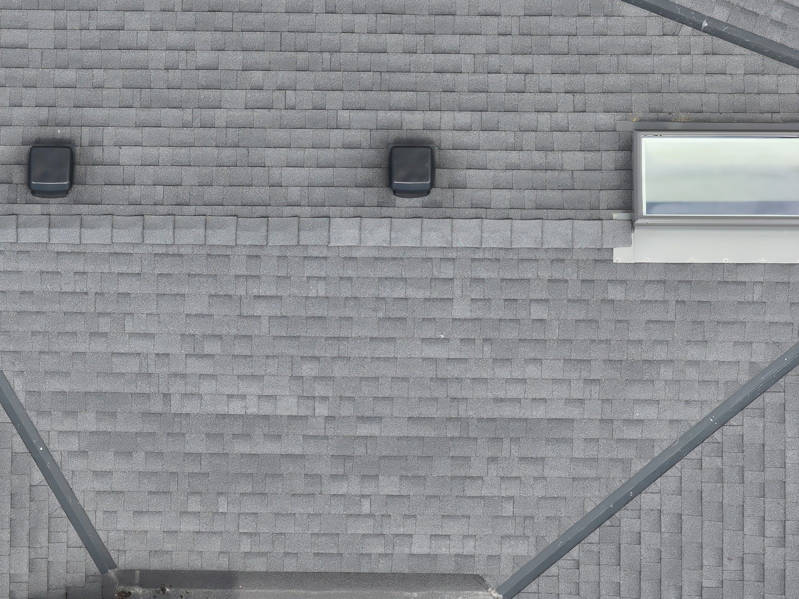 High-resolution close-up drone detail of the 1506 Johnston roof, individual shingles, flashing and ridge cap legible from a standoff distance.