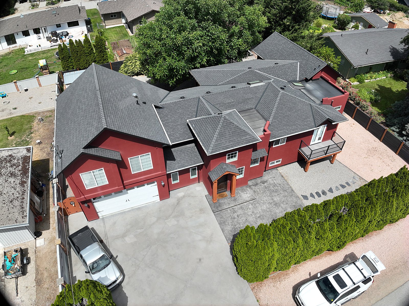 Oblique drone capture of a full residential property in Summerland, BC, the whole roof read in the context of the building and grounds.