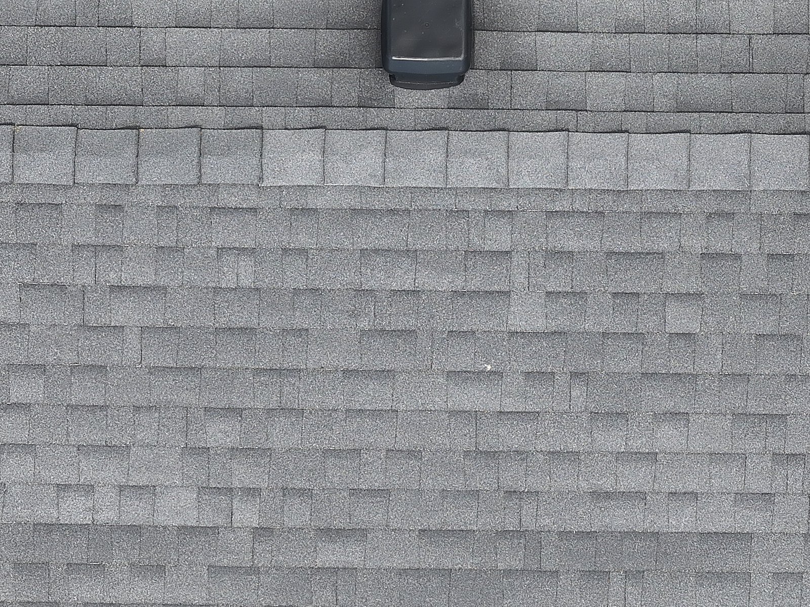 Closer drone view of a single roof plane, chimney, vents and ridge reading clearly from a safe standoff.