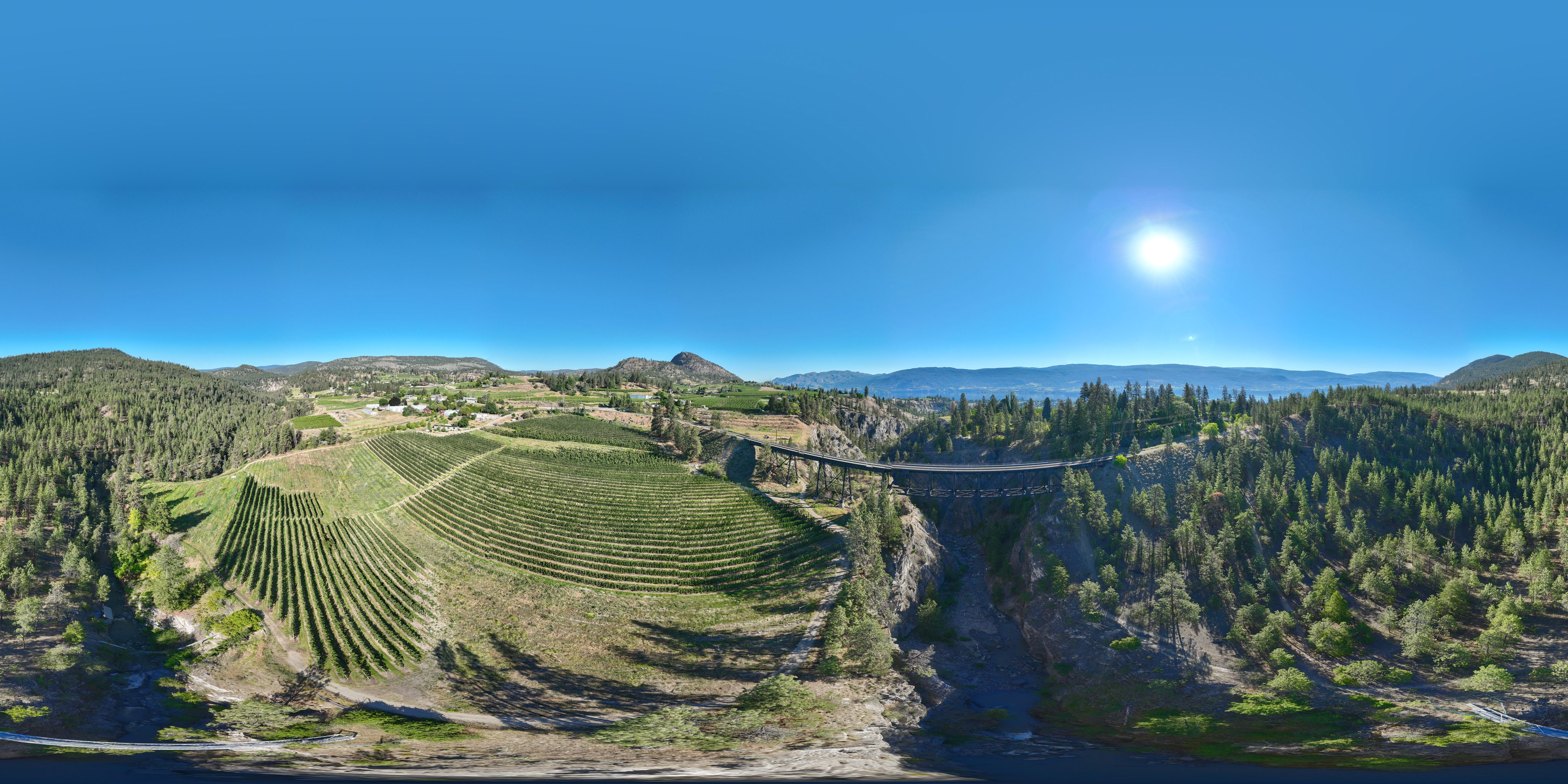 Aerial panorama of a creek-and-trestle corridor in the South Okanagan, the kind of dated shoreline-and-bank baseline imagery a restoration team sets later flights against.