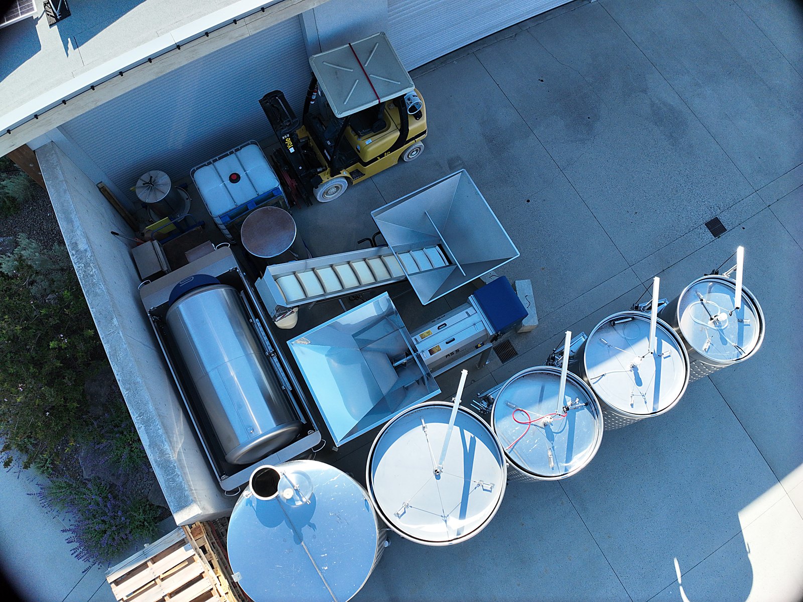 Outdoor fermentation tanks and the production yard of an Okanagan winery from above, the working back-of-house that the same single flight documents alongside the guest-facing grounds.